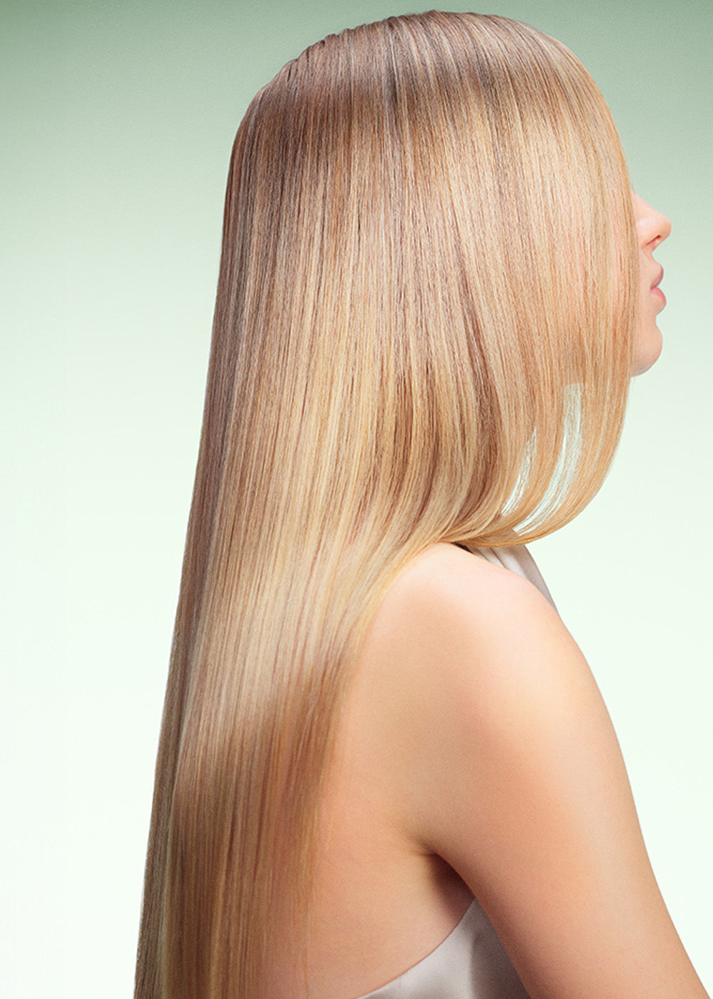 Model with long, blonde glossy hair against light green background. 